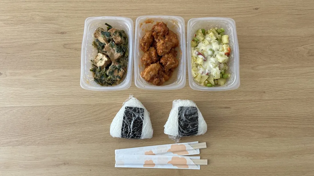 シェフの無添つくりおきの惣菜3パックと、おにぎり2個・割り箸を並べた食卓